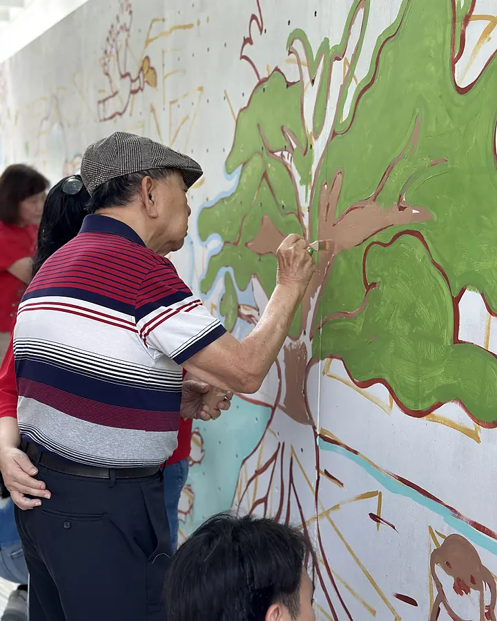 Community participant painting part of the Temasek Shophouse mural