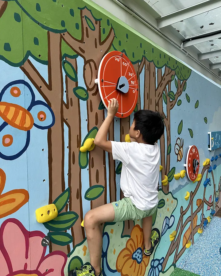 Child using an interactive panel on the finished environmental playwall